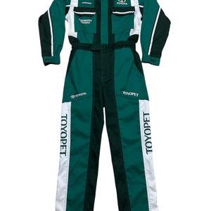May include: Green and white Toyota racing jumpsuit with the Toyota logo and "TOYOPET" printed on the legs. The jumpsuit has multiple pockets and a zip-up front. The sleeves are dark green with white accents.