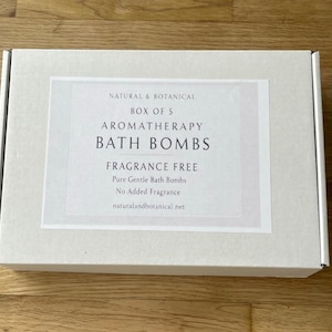 May include: A rectangular, off-white box with a label that reads "NATURAL & BOTANICAL BOX OF 5 AROMATHERAPY BATH BOMBS FRAGRANCE FREE." The label also states "Pure Gentle Bath Bombs" and "No Added Fragrance." The website naturalandbotanical.net is listed.