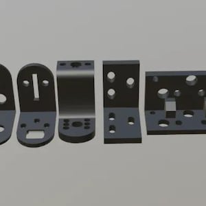 Może przedstawiać: Zbiór ciemnoszarych metalowych wsporników o różnych kształtach i rozmiarach. Wsporniki obejmują konstrukcje w kształcie litery L, prostokątne i zakrzywione, każda z wieloma otworami i szczelinami do montażu.