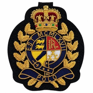Op de afbeelding: Een zwarte geborduurde patch met een gouden kroon boven een cirkelvormig embleem met de tekst EST MCMLXVIII en POLO. Het embleem is verdeeld in vier kwadranten met leeuwen, een ketting, een diagonale streep en lelies, omringd door gouden bladeren.