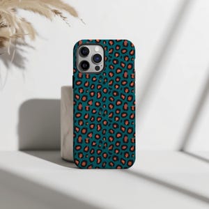 Könnte beinhalten: Eine tealfarbene Handyhülle mit Leopardenmuster. Das Muster zeigt orangefarbene Flecken, die mit Schwarz umrandet sind. Die Handyhülle wird auf einer weißen Oberfläche mit neutralem Hintergrund gezeigt.
