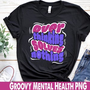 Puede incluir: Camiseta negra con la frase "Overthinking Solves Nothing" en un diseño retro y colorido. La camiseta se combina con vaqueros azules. Las palabras "GROOVY MENTAL HEALTH PNG" están en la parte inferior.