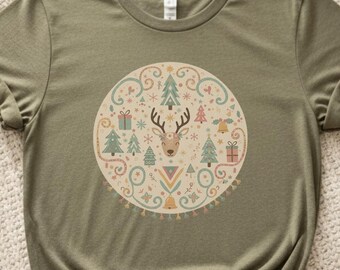Puede incluir: Camiseta verde oliva con un diseño circular que presenta un reno, árboles de Navidad y cajas de regalo en colores pastel. La camiseta tiene un nudo en la parte inferior.