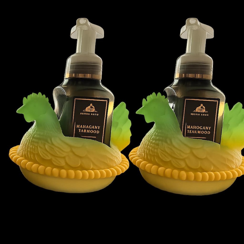 May include: Two decorative soap dispensers shaped like chickens. The dispensers are green and yellow, with a dark bottle and the text "Mahogany Teakwood". The dispensers are on a black background.