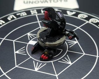 May include: A black and red toy figure with a circular base, featuring articulated sections and a detailed design. The figure is positioned on a black surface with white geometric patterns. The text "UNOVATOYS" is visible in the background.