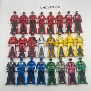 Peut inclure: Une collection de clés de figurines d'action colorées. Les clés sont de différentes couleurs, dont le rouge, le blanc, le jaune, le bleu, le vert, le gris et le rose. Le texte "UNOVATOYS" est visible en haut au centre.