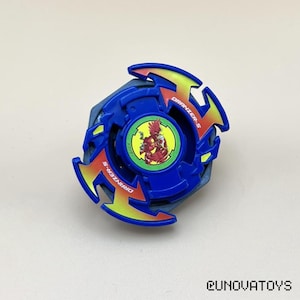 May include: A blue and yellow toy top with the text "DRANZER-S" on the side. The center of the top features a circular graphic with a red and yellow character. The toy is designed with a multi-layered construction.