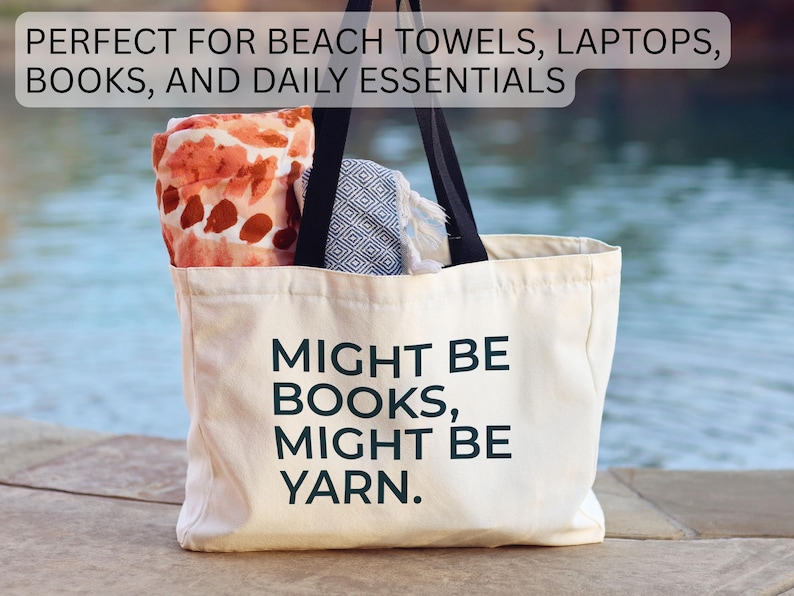 May include: A cream-colored tote bag with black handles, filled with items. The bag has the text "MIGHT BE BOOKS, MIGHT BE YARN" printed on it. The bag is filled with a patterned towel and other items.