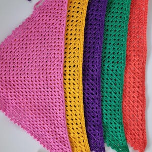 Puede incluir: Una colección de chales de ganchillo coloridos en tonos rosa, amarillo, morado, verde y coral. Cada chal presenta un diseño abierto y calado y un borde festoneado. Los chales se muestran uno al lado del otro, mostrando sus colores vibrantes.