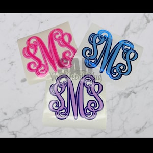 May include: Three monogram decals in pink, blue, and purple. Each decal features the letters "MS" in a decorative, swirling font. The decals are on a white background, with the text "The Decal Bug" visible.
