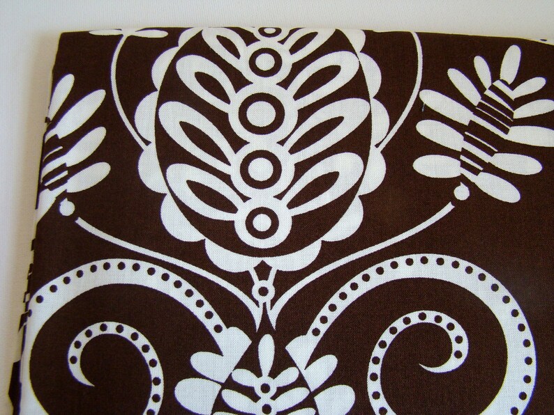 May include: Brown fabric with a white paisley pattern. The pattern features swirls, leaves, and circles.