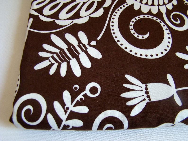 May include: Brown fabric with a white floral pattern. The pattern features swirls, leaves, and flowers.
