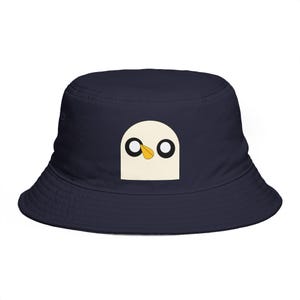 Puede incluir: Gorro de pescador azul marino con la cara de un pájaro de dibujos animados en la parte delantera. La cara del pájaro es de color crema con ojos negros y un pico amarillo. El sombrero está hecho de un material suave y tiene una forma clásica de sombrero de pescador.