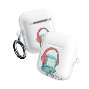 May include: Two white AirPod cases with a cartoon graphic of a blue video game console wearing red headphones. One case has a silver carabiner clip attached. The cases are angled slightly, showcasing the design.
