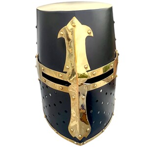 Pu&ograve; includere: Elmo medievale nero e oro con un design a croce. L'elmo ha una parte superiore arrotondata e una protezione per il viso con piccoli fori di ventilazione. Gli accenti dorati includono una croce e delle fasce.