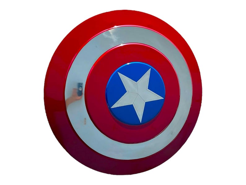 May include: A red, white, and blue Captain America shield. The shield is circular with concentric rings of red, white, and red. A blue circle in the center features a white star. The shield is a prop or collectible.