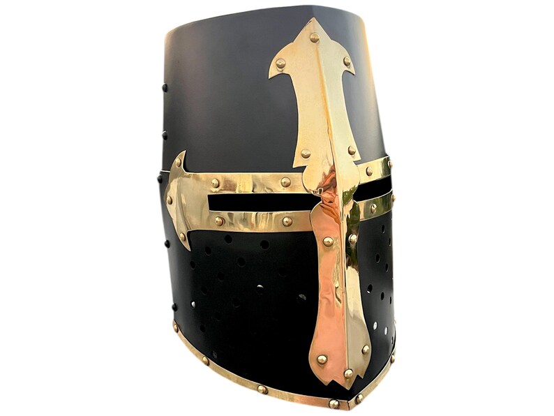 Pu&ograve; includere: Elmo medievale nero con dettagli in ottone. L'elmo presenta un design a croce e finiture in ottone. Sono visibili piccoli rivetti e fori per gli occhi. Un oggetto storico.
