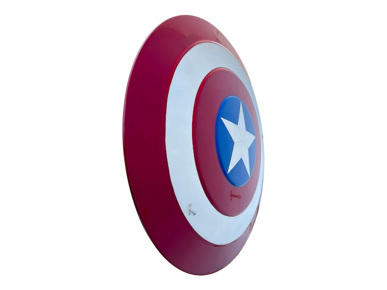 May include: A red, white, and blue shield with a star in the center. The shield has a circular design with a red outer ring, a white inner ring, and a blue center with a white star. The shield is a prop.