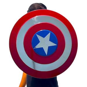 May include: A red, white, and blue shield with a star in the center. The shield has a circular design with concentric rings of red, silver, and red. The center is blue with a white star.