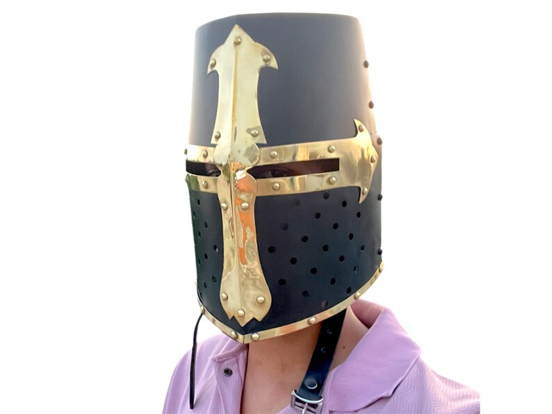 Pu&ograve; includere: Elmo nero da crociato medievale con un design a croce dorata. L'elmo presenta una parte superiore arrotondata, fori di ventilazione e un sottogola in pelle. La croce dorata &egrave; rivettata al metallo nero.
