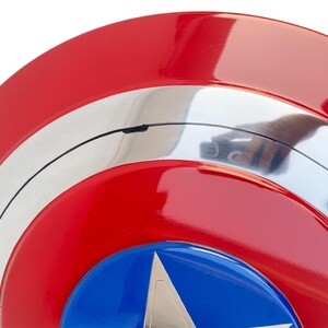 Peut inclure: Gros plan sur un bouclier rouge, blanc et bleu avec un embl&egrave;me d'&eacute;toile. Le bouclier a une finition brillante et un design circulaire. Les couleurs du bouclier sont le rouge, le blanc et le bleu.