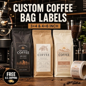Op de afbeelding: Drie koffiezakken in zwart, bruin en crème met aangepaste labels, plus een rol met zelfklevende labels. De labels bevatten tekst zoals 'SMALL BATCH ROASTED COFFEE' en bergafbeeldingen. De tekst 'CUSTOM COFFEE BAG LABELS 3x4 & 4x6 INCH' is zichtbaar.