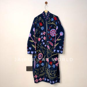 May include: A long-sleeved navy blue coat featuring vibrant floral and heart-shaped embroidery in shades of red, pink, and light blue. The garment has a mandarin collar and an open front design. The text JAIPUR FAB WORLD is visible.