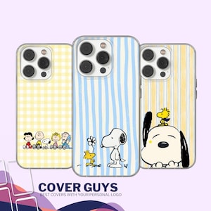 Könnte beinhalten: Drei Handyhüllen mit Cartoon-Charakter-Designs. Eine Hülle hat ein gelbes Vichy-Muster, eine andere blaue Streifen und die dritte gelbe Streifen. Die Hüllen zeigen Snoopy- und Woodstock-Charaktere. Der Text "COVER GUYS" befindet sich unten.