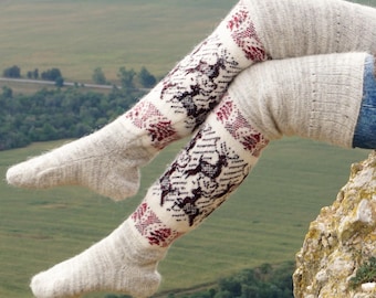 May include: Knee-high socks in a light gray color with a patterned design. The design features a repeating pattern of dark brown and burgundy shapes. The socks are made of a thick, knitted material.