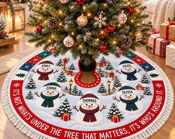 May include: A round Christmas tree skirt with a white snowy background, featuring five snowmen wearing plaid hats and scarves, each labeled with the names Emily, Hazel, Emma, Olivia, and Thomas. The text reads, It's not what's under the tree that matters, it's who's around it.