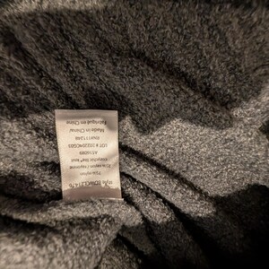 May include: Close-up of a gray knit fabric with a tag attached. The tag reads "Made in China" and lists fabric composition as 75% nylon and 25% rayon. The fabric has a soft, textured appearance.