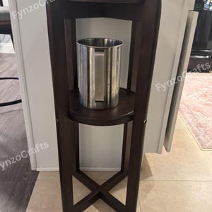 Pu&ograve; includere: Un supporto per distributore di bevande in legno marrone scuro con un secchiello per il ghiaccio in acciaio inossidabile. Il supporto ha un design a due livelli con una base a forma di X per la stabilit&agrave;. Il distributore &egrave; progettato per contenere un contenitore per bevande.