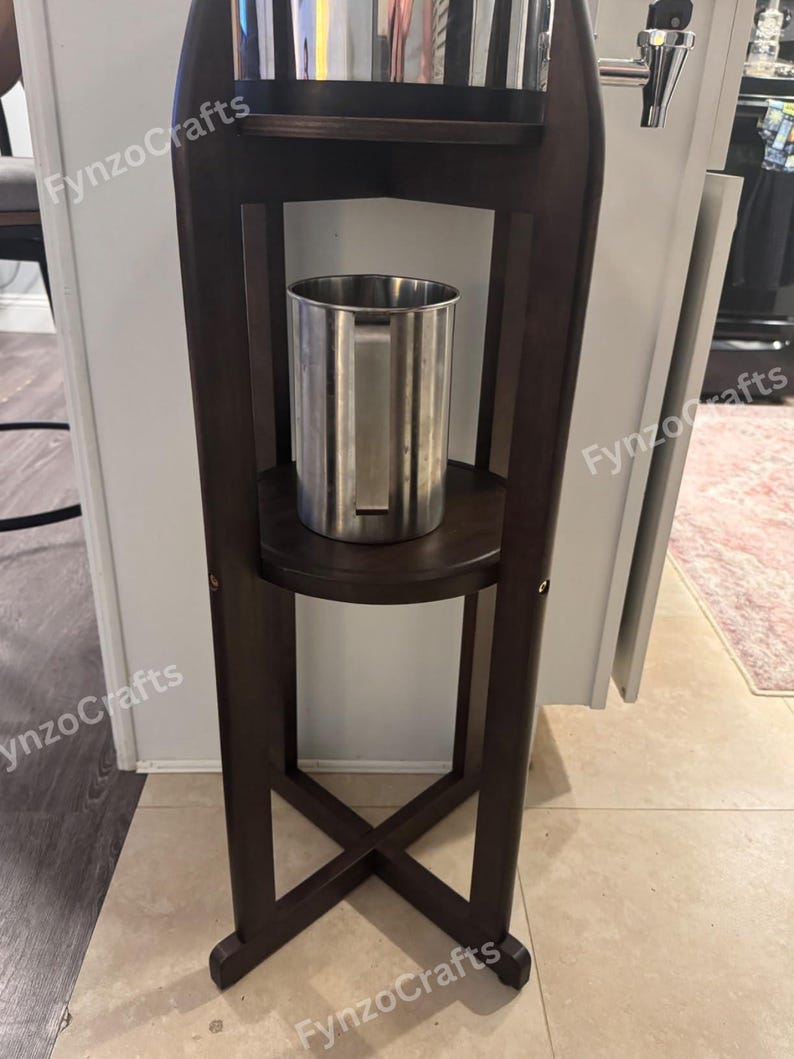 Pu&ograve; includere: Un supporto per distributore di bevande in legno marrone scuro con un secchiello per il ghiaccio in acciaio inossidabile. Il supporto ha un design a due livelli con una base a forma di X per la stabilit&agrave;. Il distributore &egrave; progettato per contenere un contenitore per bevande.