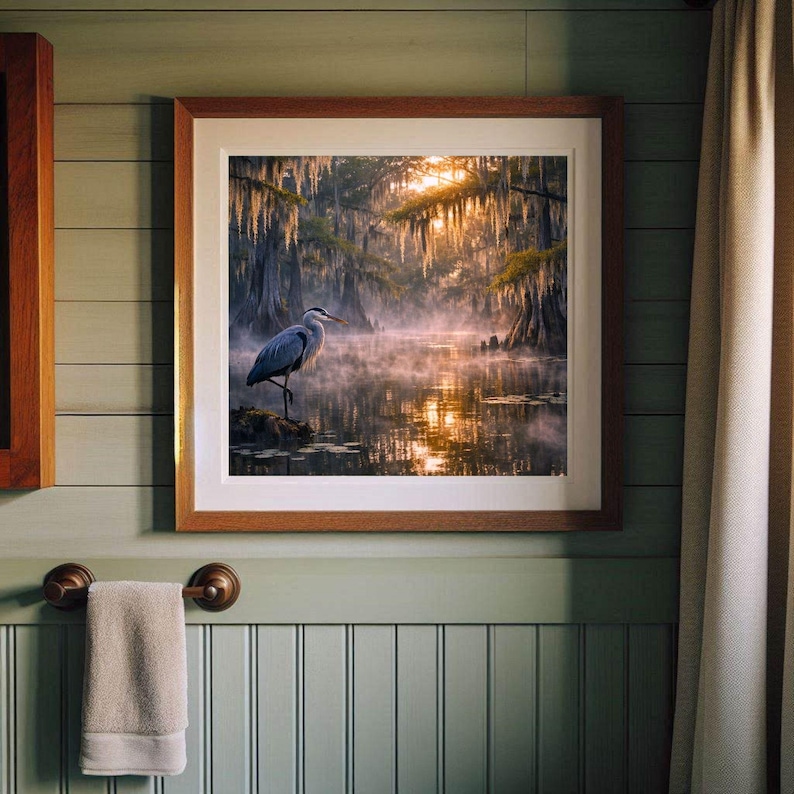 Poster | Louisiana Bayou Sunrise Print, Swamp Art, Southern Landscape, Nature Art, Tranquil Artwork

Step into the tranquil beauty of the Deep South with this atmospheric art print featuring a misty Louisiana swamp at sunrise. A majestic great blue heron stands poised on a mossy stump, its silhouette framed by golden light filtering through ancient cypress trees draped in Spanish moss. The still water mirrors the soft glow of dawn and scattered lily pads, creating a serene, dreamlike reflection.