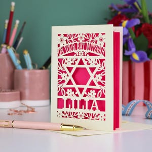 A laser cut Bat Mitzvah card with Star of David design and text "On Your Bat Mitzvah" at the top. The card is personalised with the recipient's name at the bottom and had floral and leaf design elements around the border.
