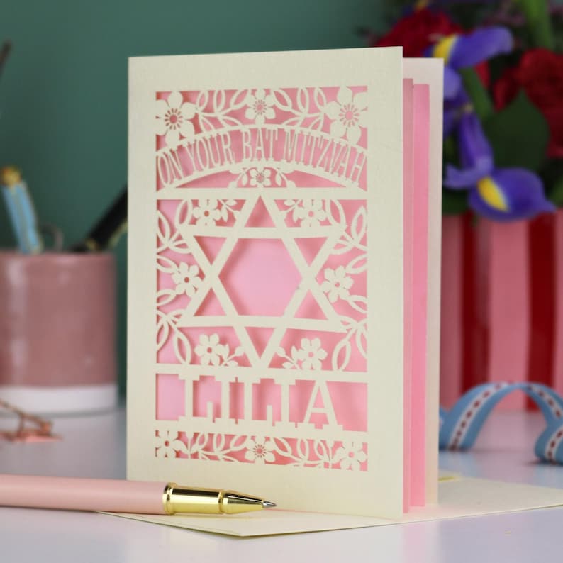 A laser cut Bat Mitzvah card with Star of David design and text "On Your Bat Mitzvah" at the top. The card is personalised with the recipient's name at the bottom and had floral and leaf design elements around the border.
