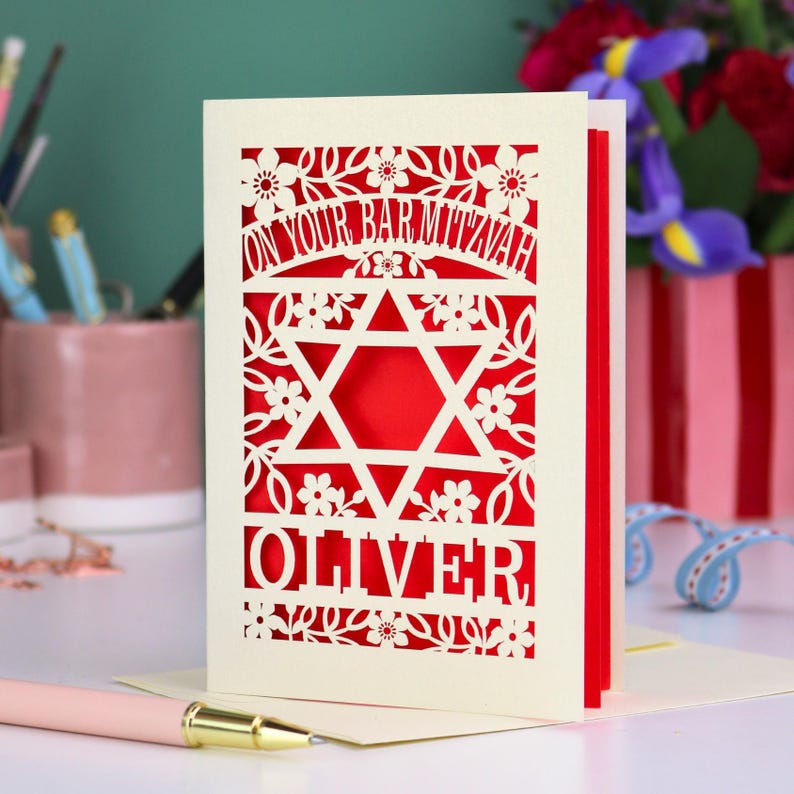 A laser cut Bar Mitzvah card with Star of David design and text "On Your Bar Mitzvah" at the top. The card is personalised with the recipient's name at the bottom and had floral and leaf design elements around the border.