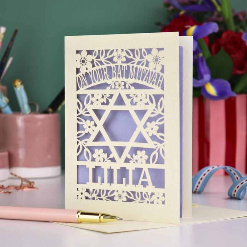 A laser cut Bat Mitzvah card with Star of David design and text "On Your Bat Mitzvah" at the top. The card is personalised with the recipient's name at the bottom and had floral and leaf design elements around the border.