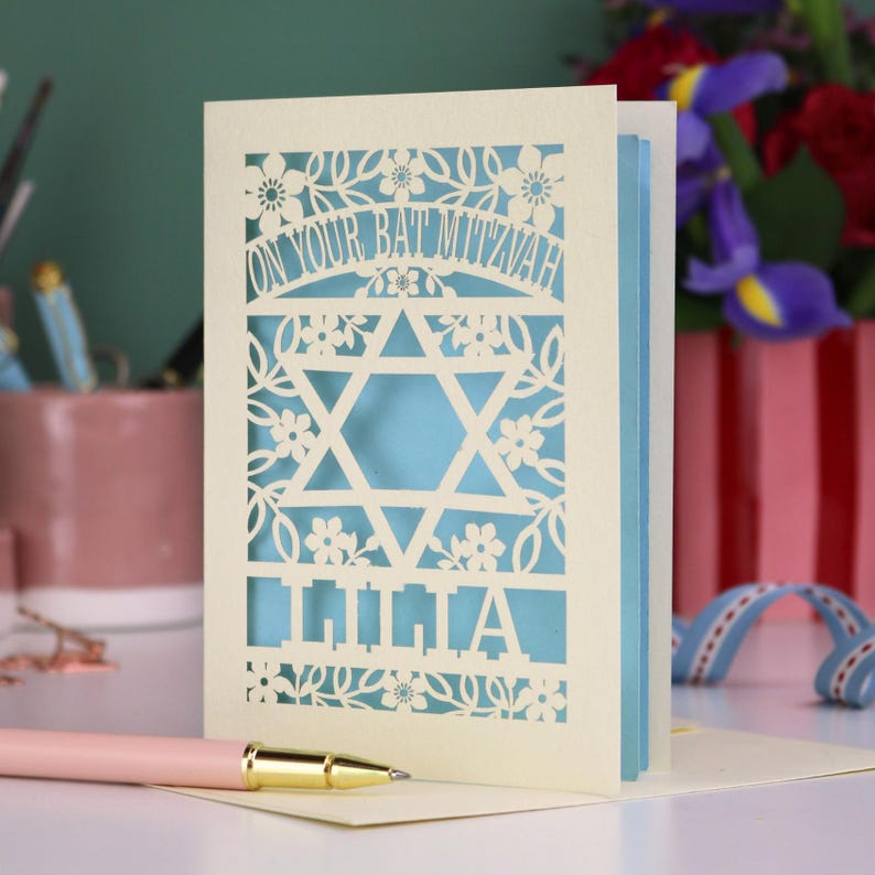 A laser cut Bat Mitzvah card with Star of David design and text "On Your Bat Mitzvah" at the top. The card is personalised with the recipient's name at the bottom and had floral and leaf design elements around the border.