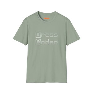 Könnte beinhalten: Salbeigrünes T-Shirt mit dem Text "Dress Coder" in Pixel-Schrift. Das Shirt hat kurze Ärmel und einen Rundhalsausschnitt. Der weiße Text ist mittig auf der Vorderseite platziert.