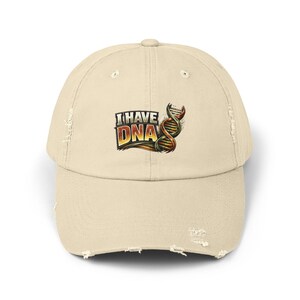 Op de afbeelding: Een beige baseballcap met een distressed look, met de tekst "I HAVE DNA" en een DNA-dubbele helix-afbeelding. De cap heeft een gebogen klep en een versleten, vintage uitstraling, met distressed details.