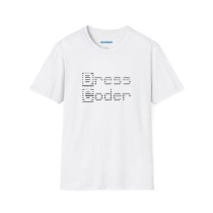 May include: A white short-sleeved t-shirt featuring a black ASCII art graphic on the chest. The design consists of two lines of text rendered in a blocky, pixelated style, creating a digital aesthetic on the front of the garment.