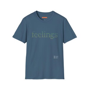 Könnte beinhalten: Ein blaues T-Shirt mit kurzen Ärmeln und dem Wort "feelings" in einem pixeligen grünen Schriftzug auf der Brust. Das Shirt hat einen Rundhalsausschnitt und ein kleines orangefarbenes Etikett am Ausschnitt. Der Markenname "Dress Coder" ist unten rechts aufgedruckt.