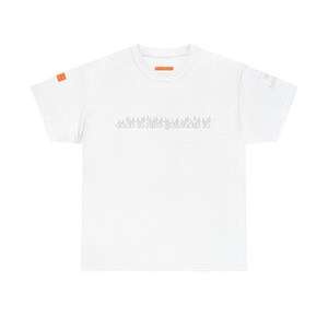 Puede incluir: Una camiseta blanca de manga corta con una pequeña etiqueta rectangular naranja en la manga izquierda y una etiqueta naranja más grande en el interior del cuello. El pecho muestra el texto "love it like you stole it" en letra fina.