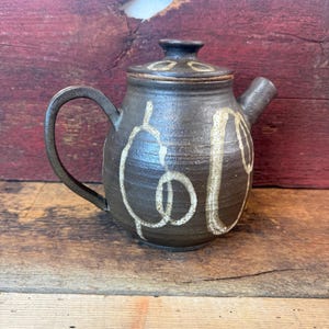 Collectible Japanese Tea Pot. Hand-thrown art studio pottery featuring a dark textured stone glaze & White Geometric shapes. Artist signed.