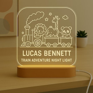 May include: A personalised night light with a train design featuring a lion, elephant, giraffe, and panda. The text "LUCAS BENNETT TRAIN ADVENTURE NIGHT LIGHT" is displayed on the light, which sits on a wooden base.