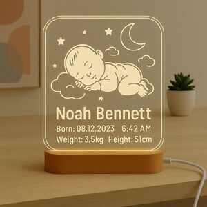 May include: A personalised night light with the name "Noah Bennett" etched on it. The design features a sleeping baby, stars, a crescent moon, and clouds. The light also displays the baby's birth date, time, weight (3.5 kg), and height (51 cm).