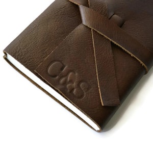 May include: A brown leather journal with a knotted leather closure and the initials "C.M.S." embossed on the front cover.