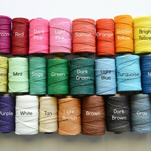 May include: A collection of 24 spools of thread in various colors, including maroon, red, dark pink, light pink, salmon, orange, golden yellow, bright yellow, chartreuse, mint, sage, green, dark green, light blue, turquoise, navy, lavender, purple, white, tan, light brown, brown, dark brown, gray, and black.