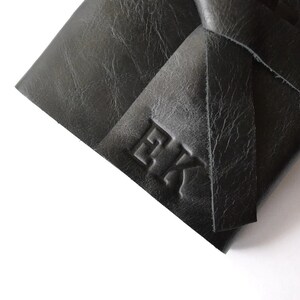 May include: Black leather journal with a knotted closure and the initials "EK" embossed on the front.